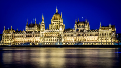 Fototapeta na wymiar Illuminated Hungarian Parliament at night with yellow light and water reflection. Budapest, Hungary.