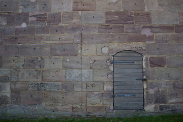 A wooden door against a stone wall. Walk near the Castle