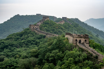 Fototapeta na wymiar Great Wall of China with a green trees in a background.