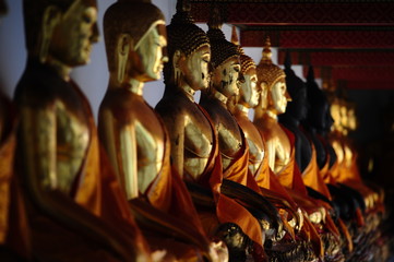Statue di Buddha dorati seduti in linea al Wat Pho