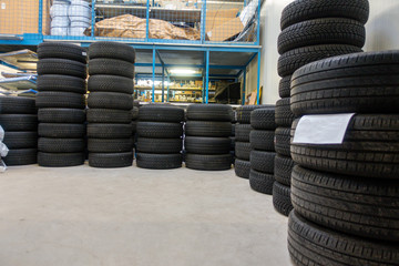 in a garage, many new tyres are stacked so that they can be fitted as winter tyres