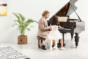 Man teaching little girl to play piano
