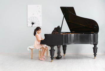 Little girl playing grand piano indoors