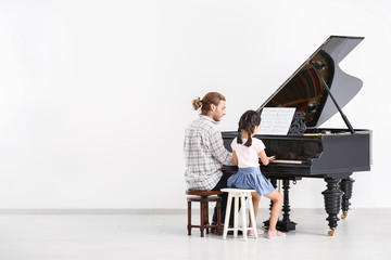 Man teaching little girl to play piano © Pixel-Shot
