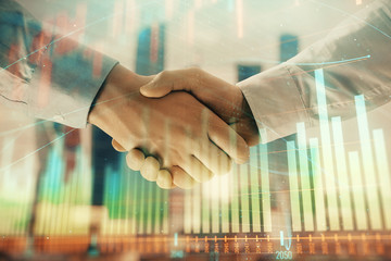Double exposure of financial graph on cityscape background with two businessman handshake. Concept...