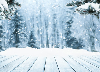 Wooden table top on winter sunny landscape with fir trees.