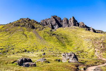 A scenic landscape on the Isle of Skye near The Old Man of Storr, with a clear blue sky overhead