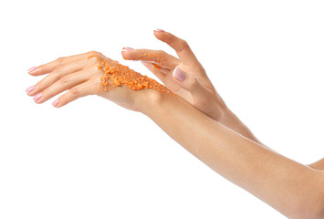 Beautiful young woman applying body scrub against white background