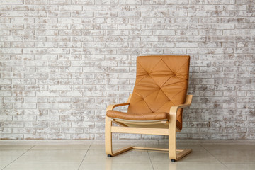 Stylish armchair near brick wall