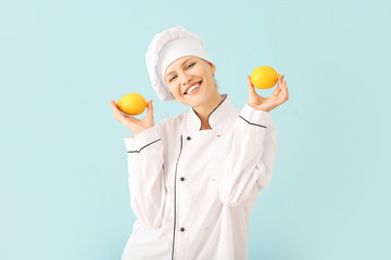 Beautiful female chef with lemons on light background