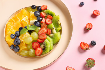 Plate with tasty fruit salad on color background
