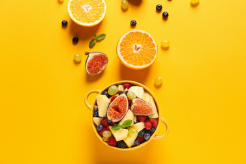 Pot with tasty fruit salad on color background