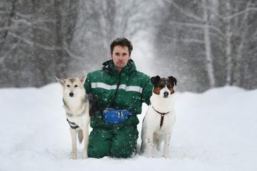 Two dogs walk outdoors in winter with an owner