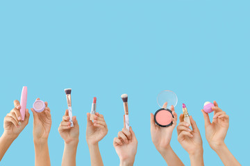 Many hands with decorative cosmetics and makeup brushes on color background