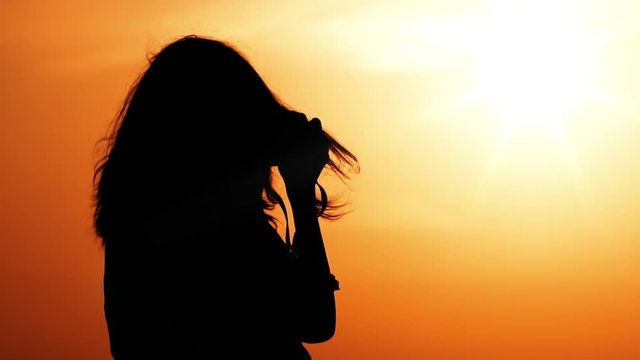 traveller shoot outdoors silhouette of woman with long fluttering hair holding camera shooting landscape slow motion