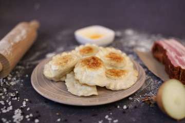 Traditional dumplings stuffed with cheese, fried potatoes and bacon in a frying pan until golden brown