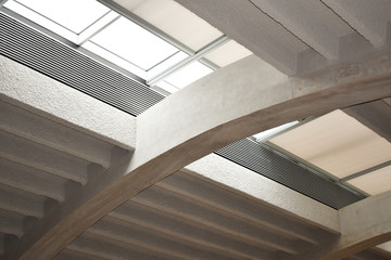 Obraz premium Modern white concrete arched ceiling with top windows and ventilation grilles.