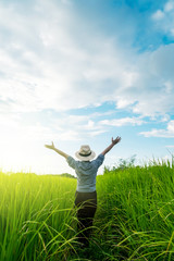 Behind the farmer woman's hands raised in the sky in a field with sky background