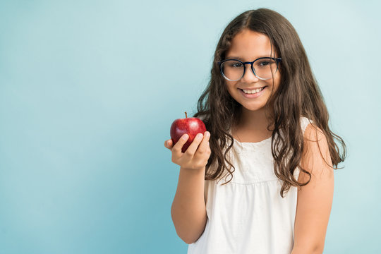 Cute Girl With Healthy Fruit Standing Against Plain Background