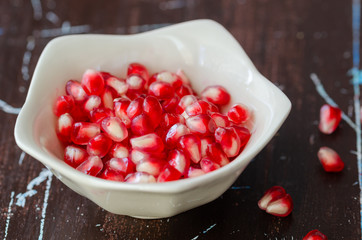 Pomegranate seeds in white bowl