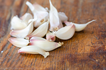 White garlic  cloves on wooden cutting board.