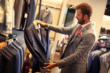 Businessman choosing suit in clothing store