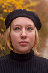 Blondy girl in black sweater and beret stands in the autumn in the park