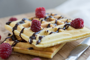 Two Viennese waffles with chocolate and berries on a wooden Board