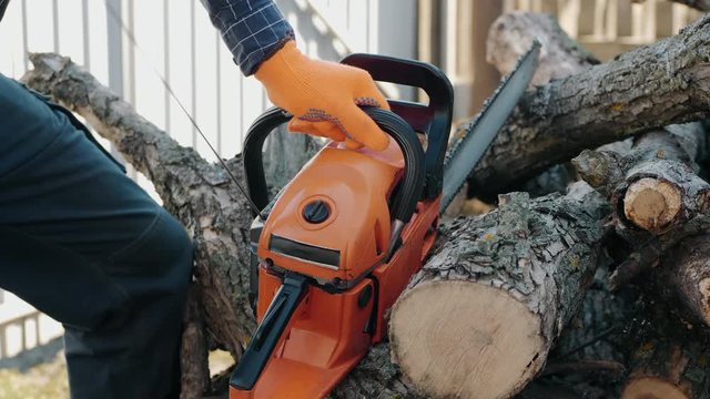 A forester desperately trying to start his chainsaw in the backyard, close-up