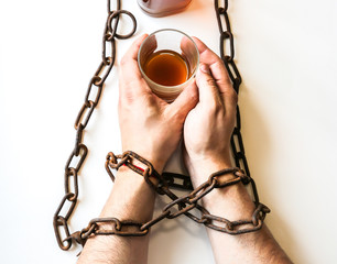 Man's hands in old rusty chains near the bottle. Addicted to alcohol. Dangerous habit.