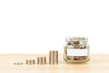 Coin glass jar container and stack on wooden desk with blank label, on white background