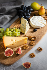 Various kinds of cheese served on wooden board, traditional pieces of french and italy hand-made cheese. Delicacy, dairy products, healthy nutrition, keto diet