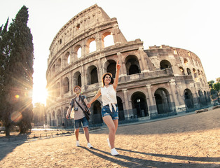 Young happy couple of tourist walking holding hands at Colosseum. Come with me. Rome, Italy - obrazy, fototapety, plakaty