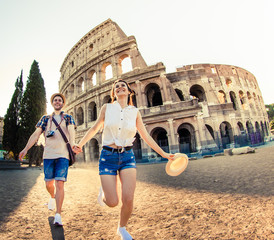 Young happy couple of tourist walking holding hands at Colosseum. Come with me. Rome, Italy