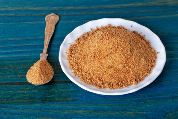 A plate and a spoon with brown sugar on blue