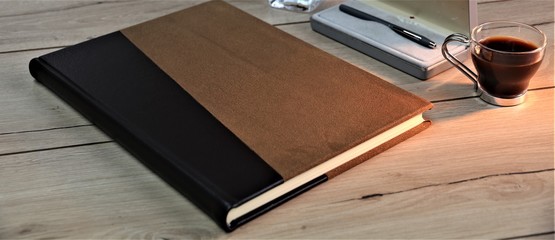 notebook on wooden table with coffee and pen
