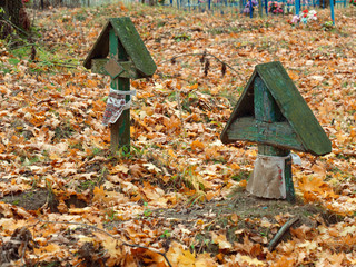 old wooden cross on a grave in a cemetery in autumn
