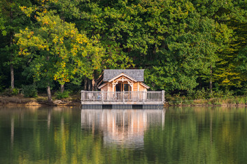 Fototapeta na wymiar une maison sur pilotis sur un lac avec une forêt. Une maison écologique en bois sur l'eau. 