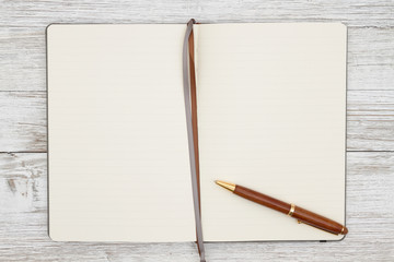 Blank brown journal with pen on a weathered whitewash wood background