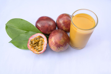 A glass of fresh passion fruit with cut out with seeds yellow flower on green leaves on white background, Isolated.