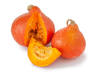 Two ripe red decorative pumpkins close-up on a white background with a piece cut off from one of them. Isolated. Copy space