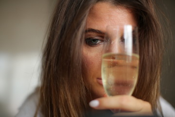 Portrait of an alcoholic woman who hides half of her face with a glass of alcohol.