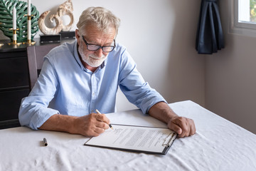Senior old man elderly examining and signing last will and testament - obrazy, fototapety, plakaty