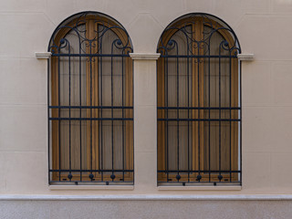 Two vintage windows with iron grating on a stone wall. Valencia, Spain