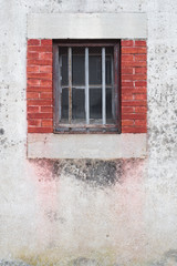 Une vieille fenêtre sécurisée avec des barreaux de sécurité. Une vieille fenêtre entourée de briques.