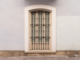 Vintage window with iron grating on a stone wall. Valencia, Spain