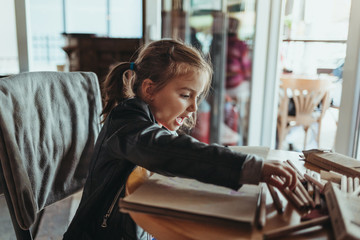 Adorable preschool girl drawing with wooden pencils in a cozy cafe. Cute daughter smiling and drawing colorful shapes for kindergarten homework