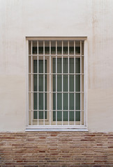 Modern window with iron grating on a stone wall. Valencia, Spain