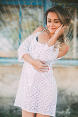 Beautiful and sexy girl in a white light dress on a bright Sunny day next to the old staircase