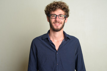 Face of happy young bearded businessman with eyeglasses smiling